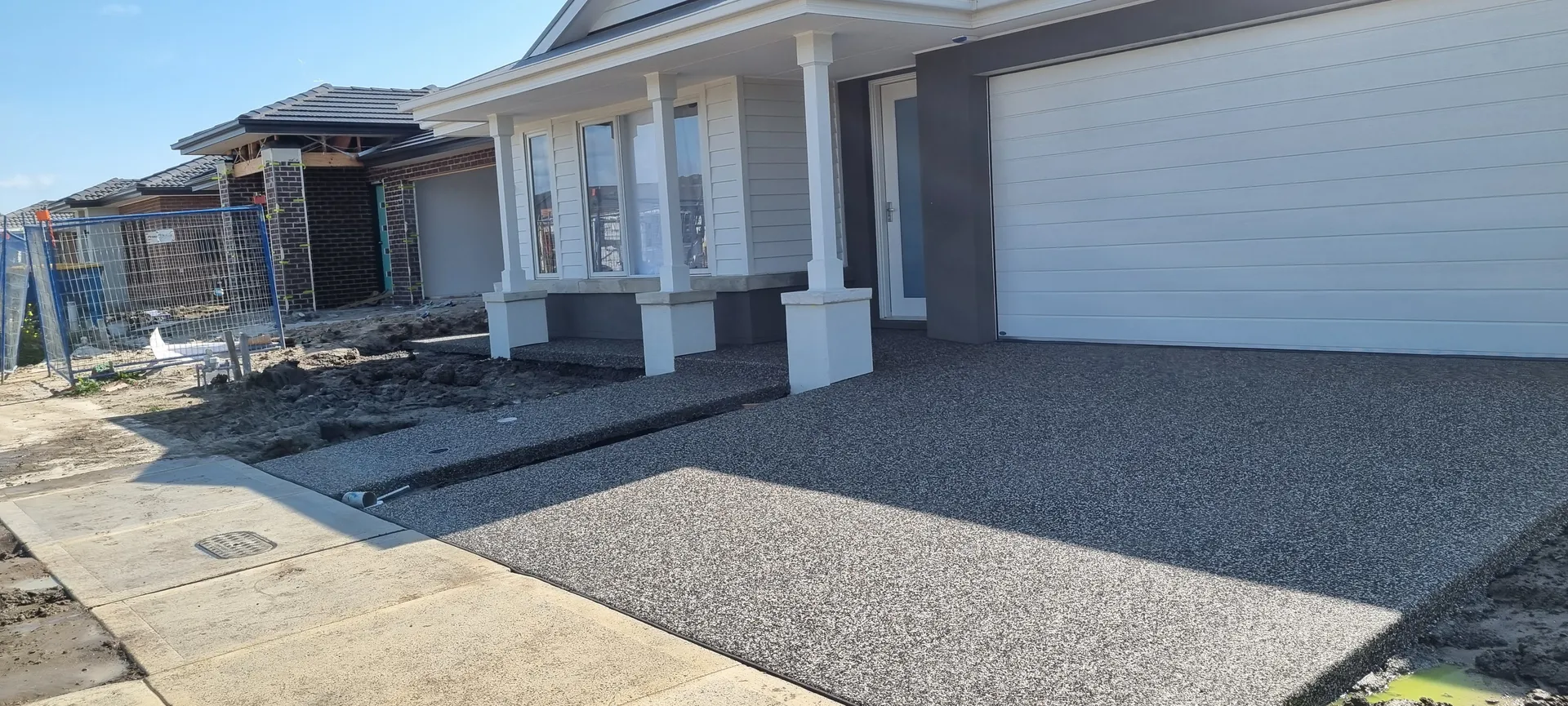 Wide exposed aggregate driveway — full frontage, grey stone finish