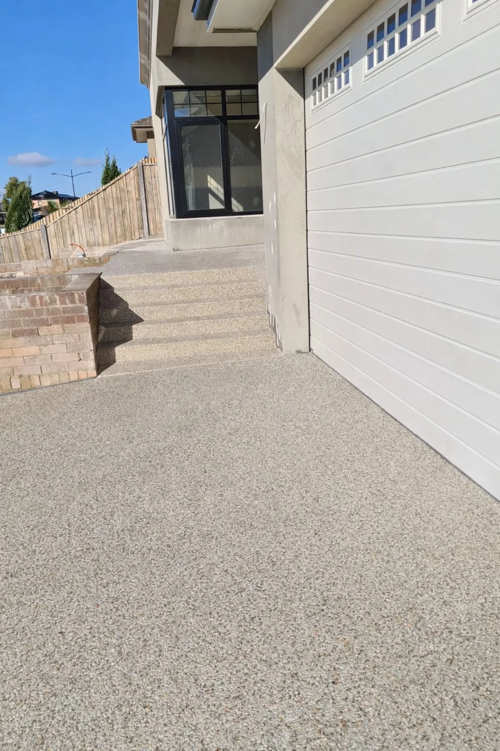 Exposed aggregate driveway and matching steps — warm stone finish, residential new build